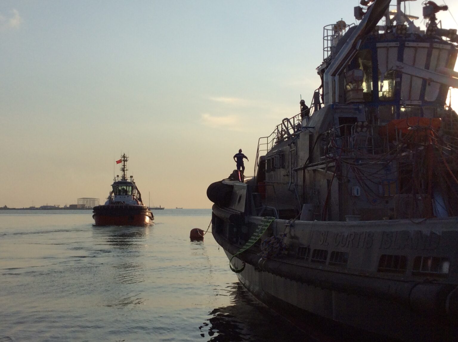 Vessel and tug operations on the water at sunset